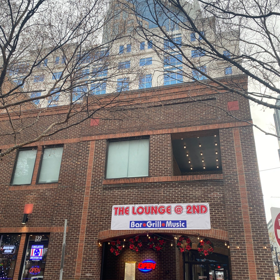 The Lounge @ 2nd bar-and-grill building exterior with a banner sign and festive wreaths.